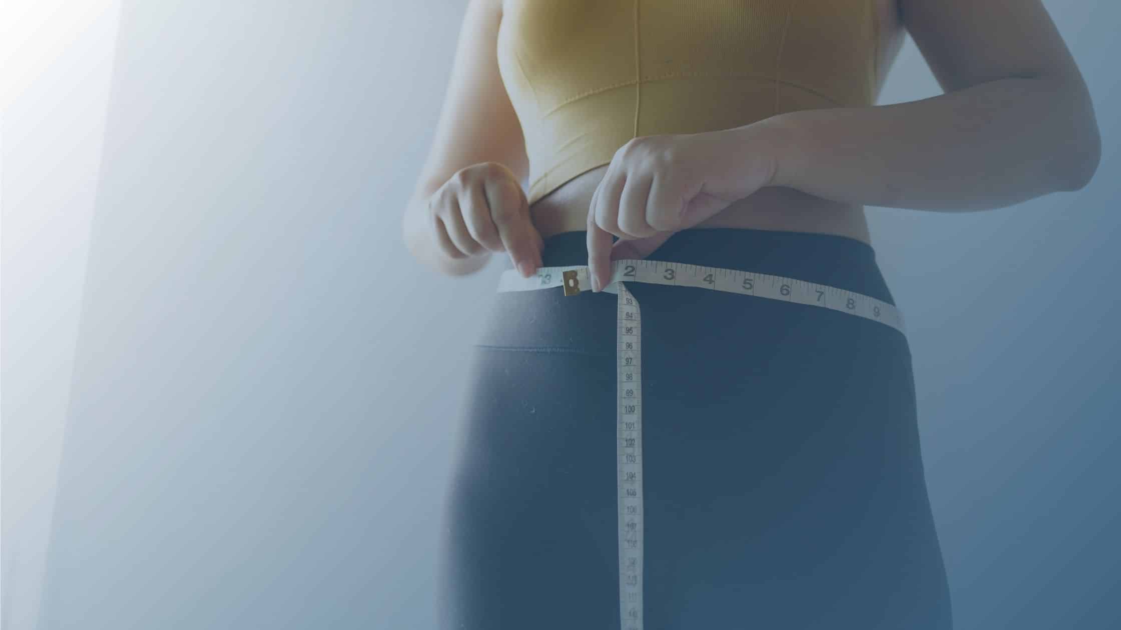 Pessoa medindo a circunferência abdominal com uma fita métrica, simbolizando o acompanhamento da perda de peso.